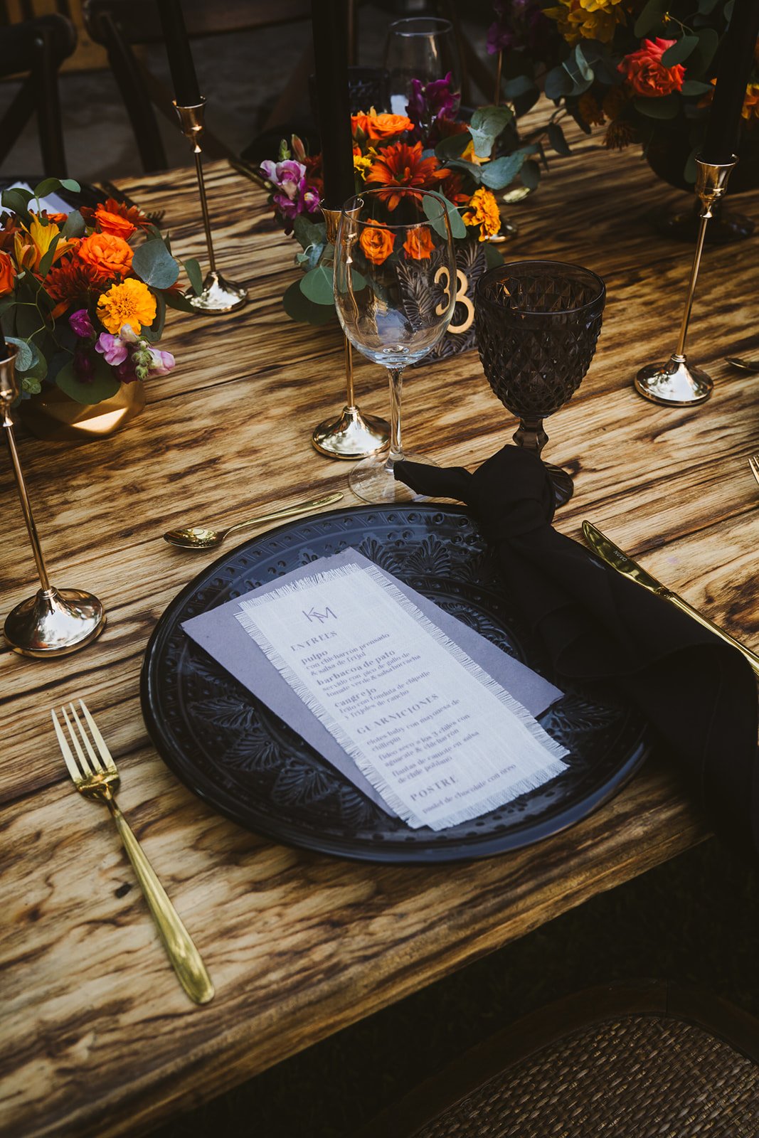 Montaje de mesa con flores en tonos naranja y papelería personalizada
